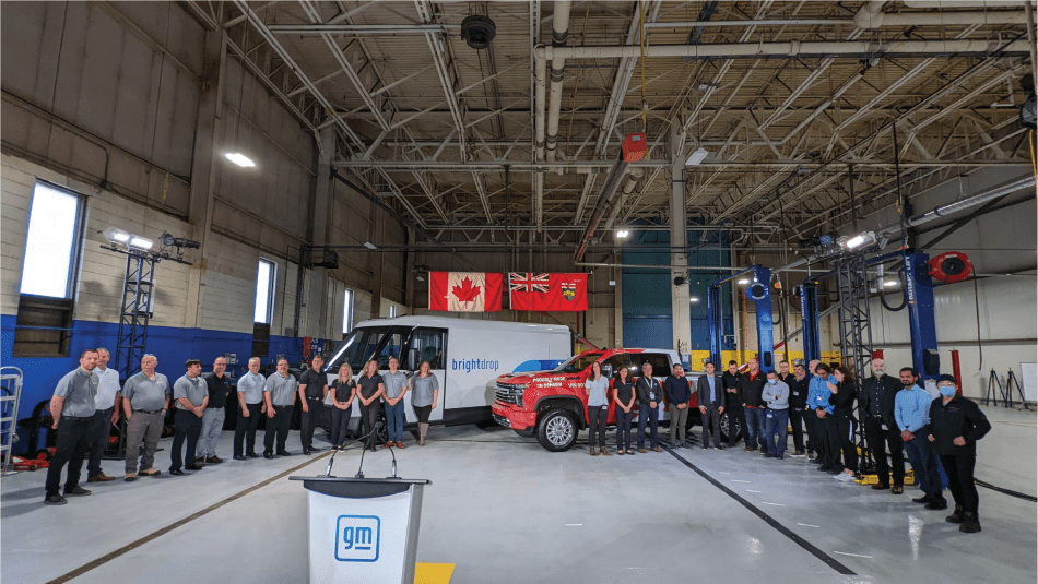 Unifor members stand together at the GM Oshawa test track in front of a Chevy Silverado assembled at the Oshawa plant and a BrightDrop commercial electric vehicle being built by workers at the CAMI plant in Ingersoll. 