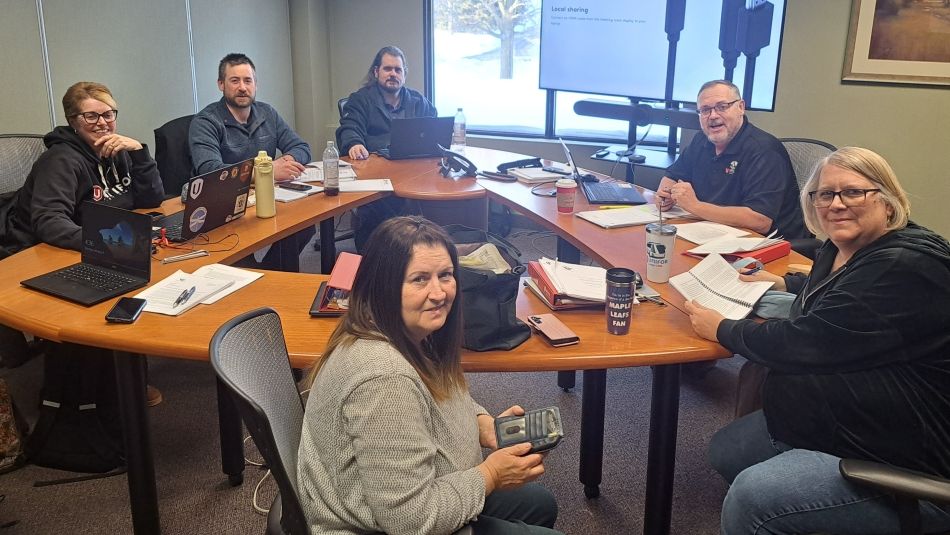 A group of six people sitting around a table smiling at the camera