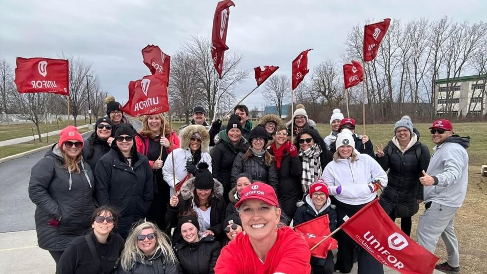 Group of people holding red Unifor flags