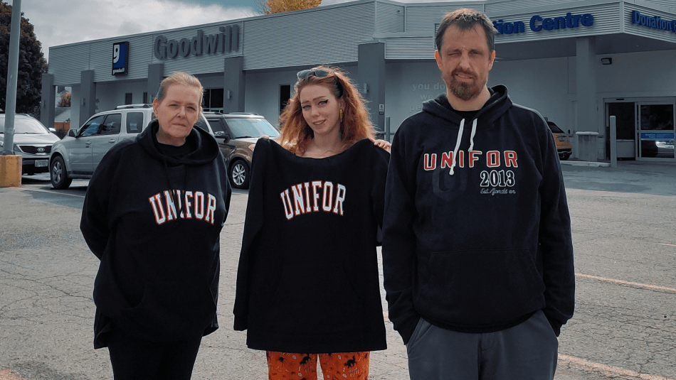 Trois personnes debout à l'extérieur, vêtues de sweatshirts Unifor