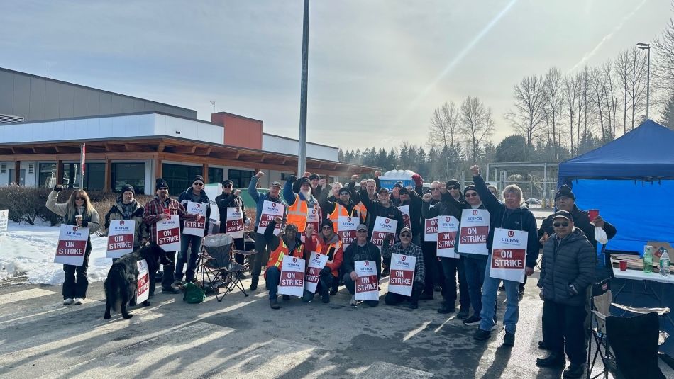 A group of Unifor workers holding strike signs outdoors.