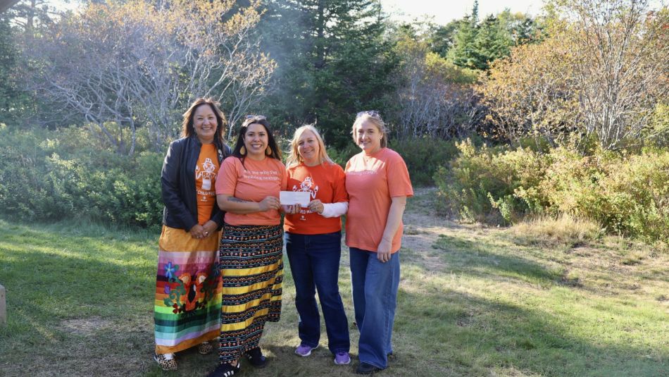 four people outside holding up a cheque