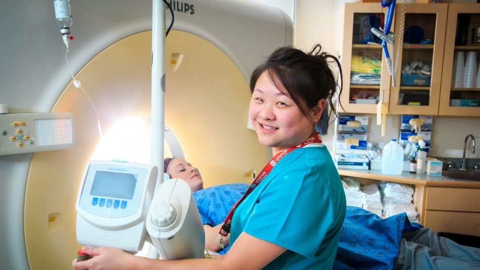 A women lying on a CT scan machanie and a nurse standing in front of the medical equipment 