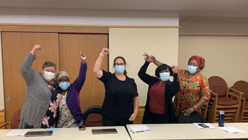 Five members of the Unifor Local 8300 bargaining committee raise their fists in the air after negotiating first collective agreement at Hillel Lodge.