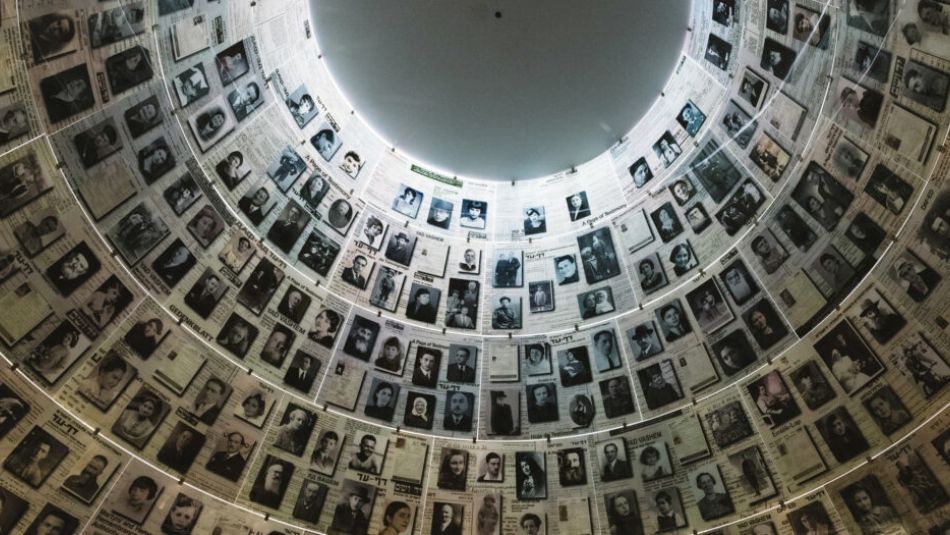 Framed photos of Holocaust victims line a dome shaped cathedral ceiling.