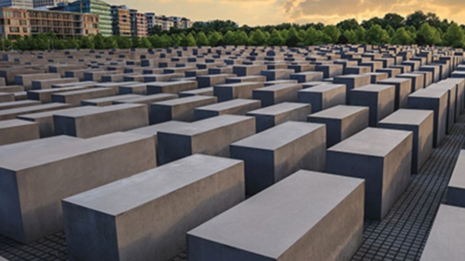 Large rectangular stone blocks are lined up into the distance at a Holocaust memorial in Berlin.	
