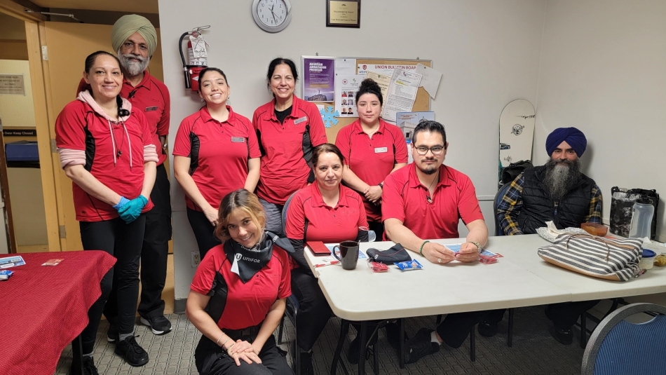 A group of workers in matching red shirts posed in an office.