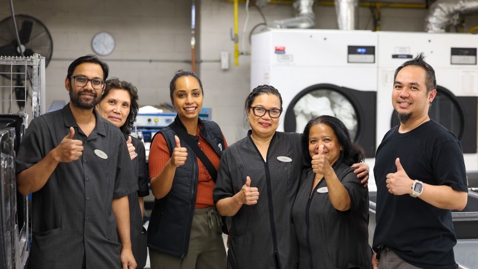 A group of hospitality workers posing with thumbs up