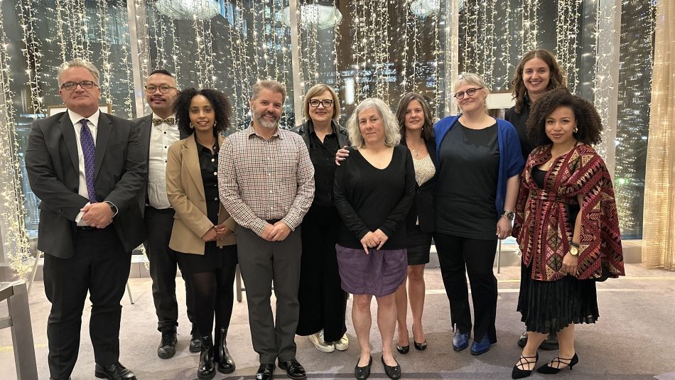 A group of people standing in front of a window strung in fairy lights