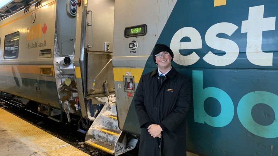 Smiling man standing in front of a Via train.