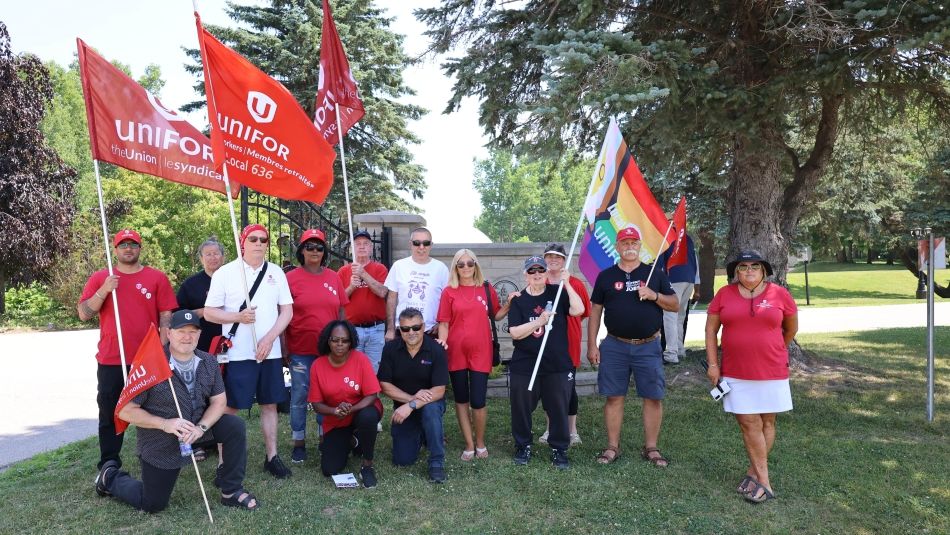 group of people outside with Unifor flags 