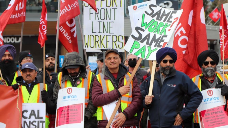 Plusieurs personnes tenant des drapeaux et des pancartes d’Unifor participent à un rassemblement