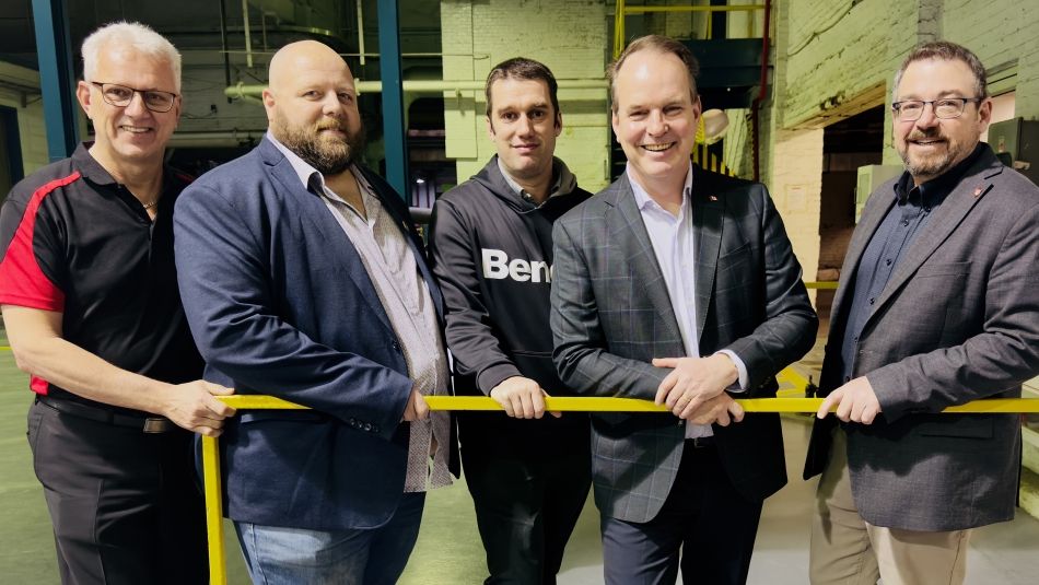 cinq hommes dans une usine près d'une balustrade jaune
