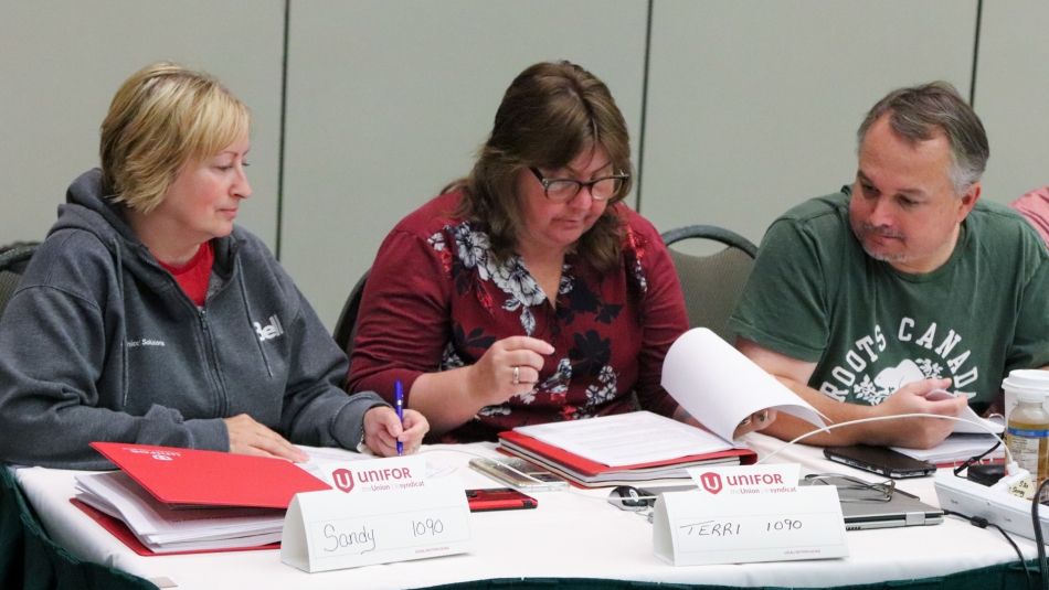 Trois membres du comité de négociation assis à une table examinent ensemble des documents
