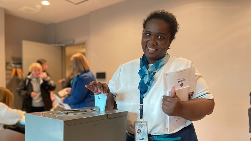 A back women places a ballot in a ballot box
