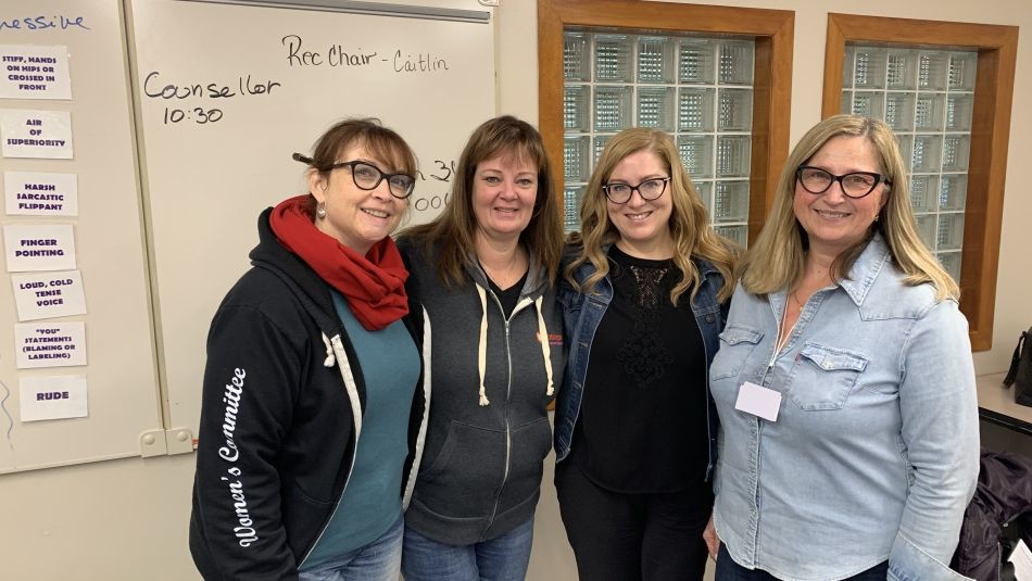 Four women standing smiling.