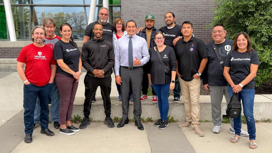 Unifor members posing for with Wab Kinew outdoors.