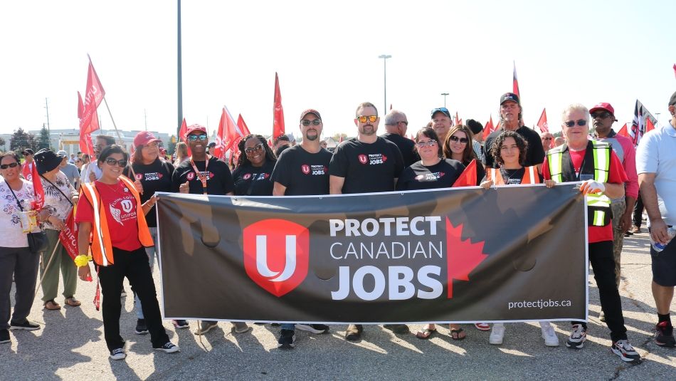 A group of people holding a ‘Protect Canadian Jobs’ banner 