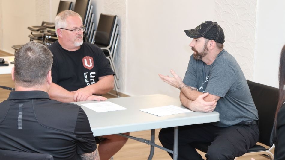 Three men sitting at a table talking.