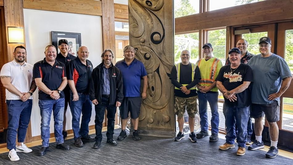 Unifor representatives at Tseshaht First Nations offices Dix personnes se tenant à l'intérieur à côté d'un totem.