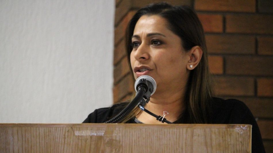 A woman speaks at a podium into the microphone.