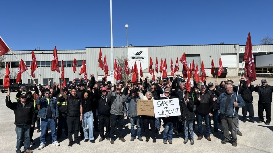 Un grand groupe de personnes brandissant des drapeaux, deux personnes à l'avant brandissant des pancartes.