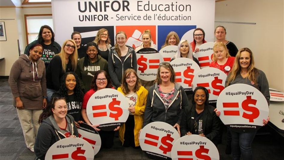 A large group holding up Equal Pay signs