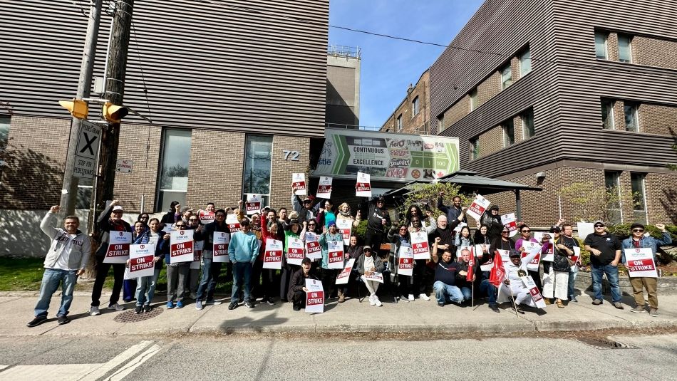 A large group of people standing holding up flags and on strike place cards