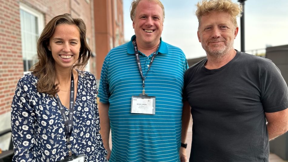 Three people pose outdoors.