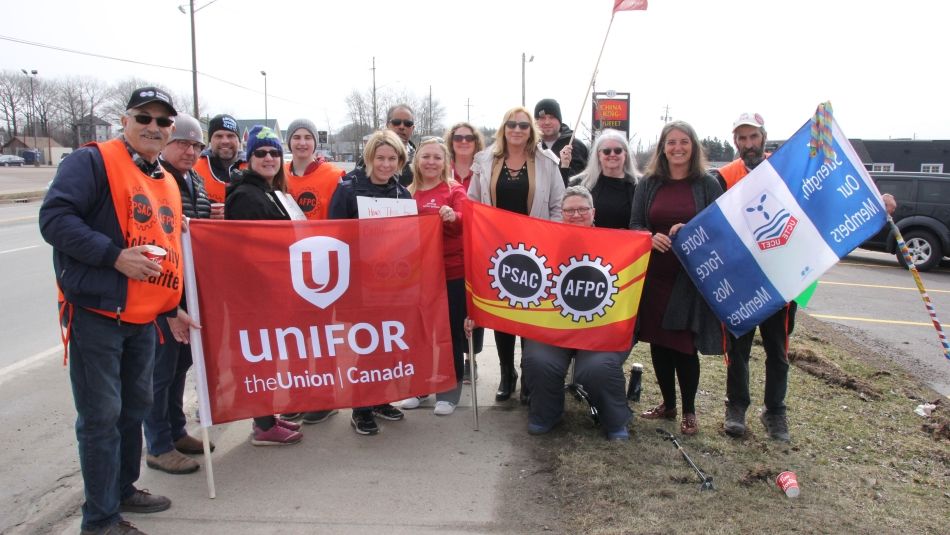 Les dirigeants d'Unifor et les membres de l'Atlantique posant avec des drapeaux sur le piquet de grève de la PSCA.