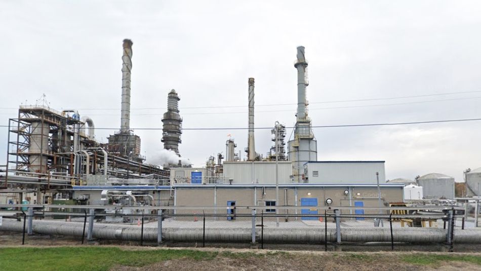 A chemical industrial site with several smoke stacks, windowless buildings, and several storage tanks.