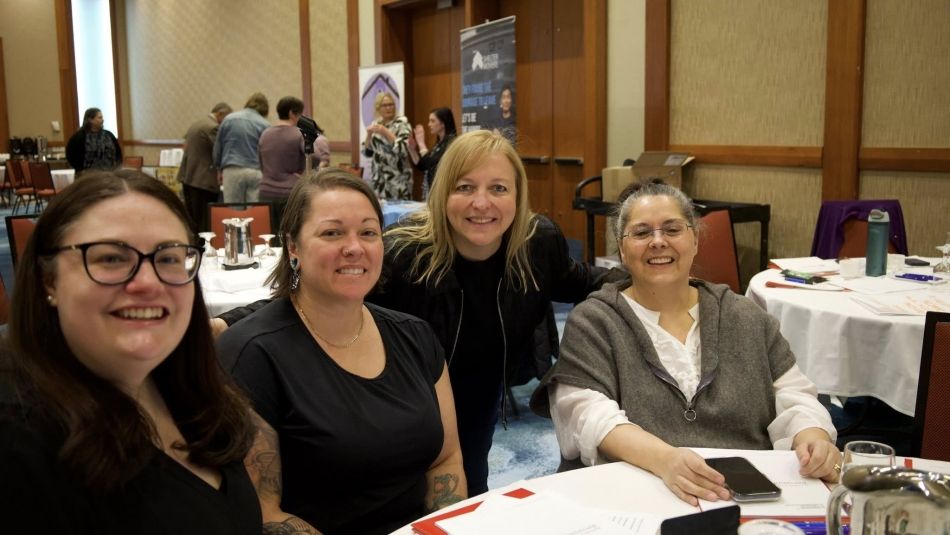 Four women sitting at a table smiling