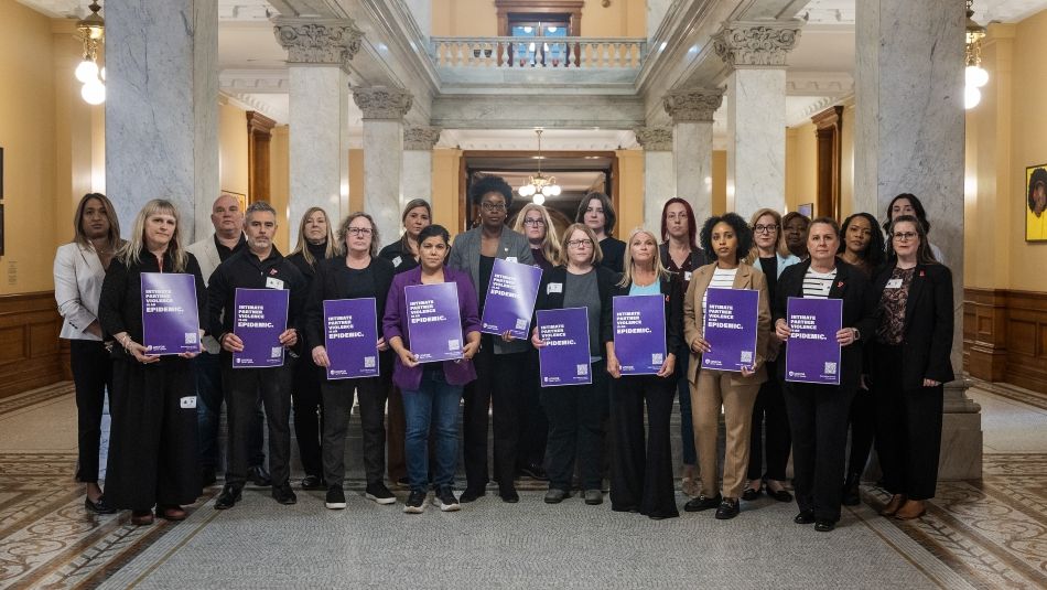 A large group of women holding purple IPV placards