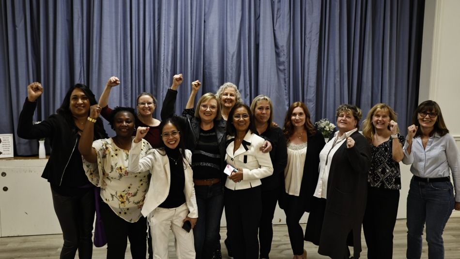 A group of Unifor sisters many holding their fists in the air in solidarity.