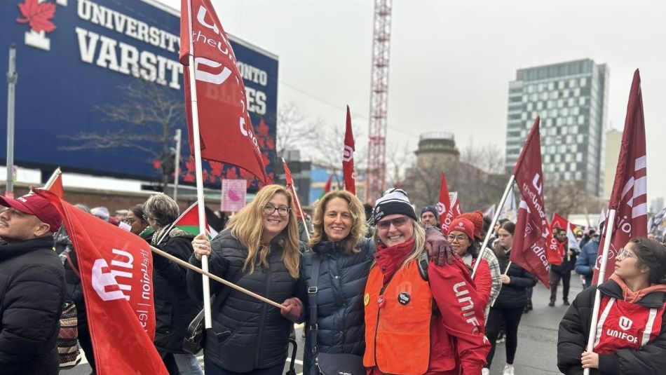 Unifor Women's Department Director Tracey Ramsey, holding a red Unifor flag, with Unifor staff and members at rally.