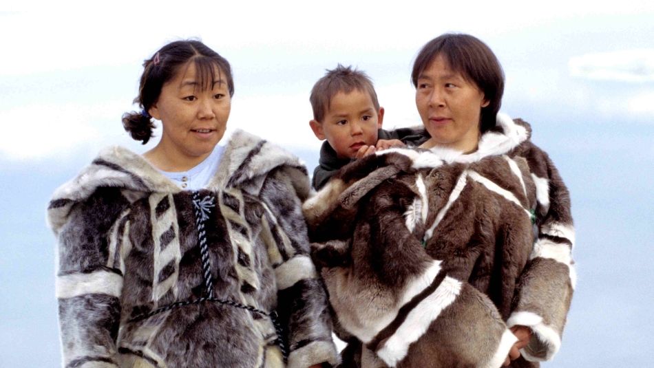 Two Iglulingmiut Inuit women in traditional parkas, one is carrying a child behind her