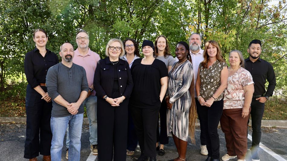 A group of people outside in front of green trees