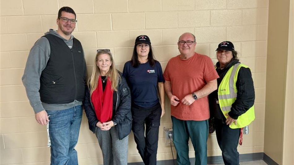 Five people posing by a beige wall