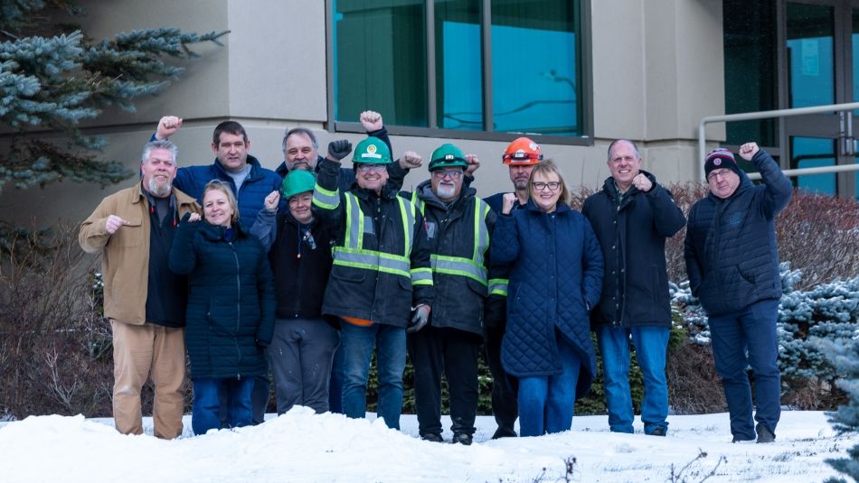 A group of people stand in front of a building with raised fists.