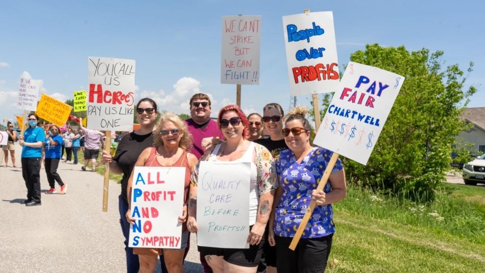 Woker's picketing holding signs outside a long term care home