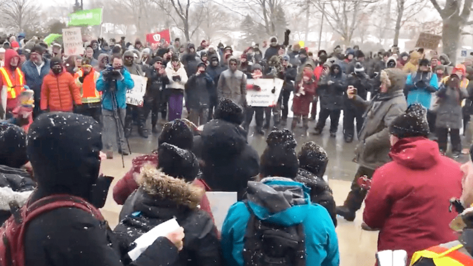 A Unifor flag flying in a large crowd of supporters at a MUNFA rally.