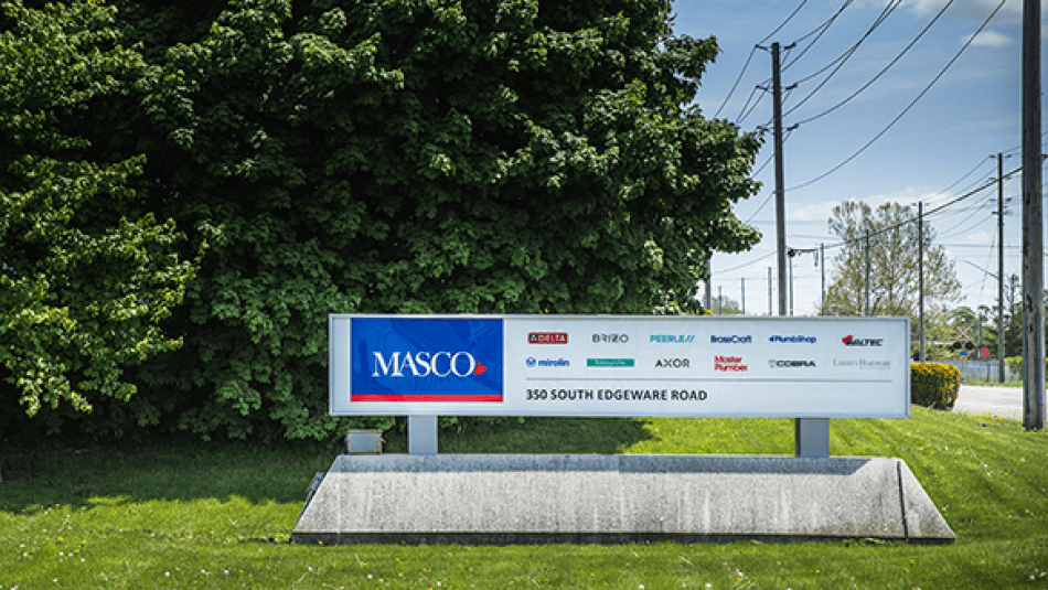 A blue Masco logo exterior sign with bushy tree in the background.