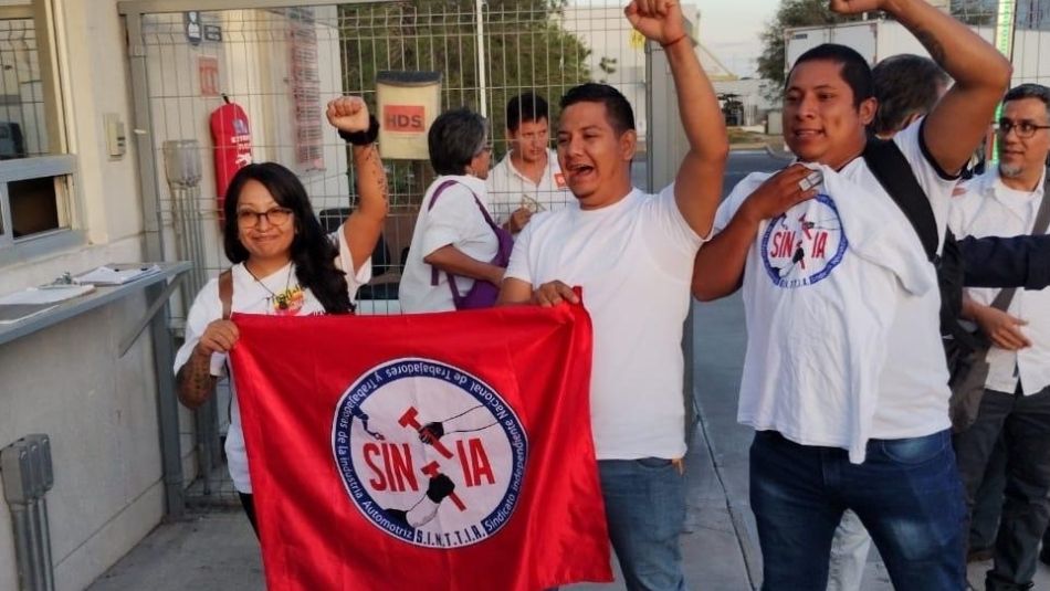 A group of people with fists raised in the air, with a red flag.