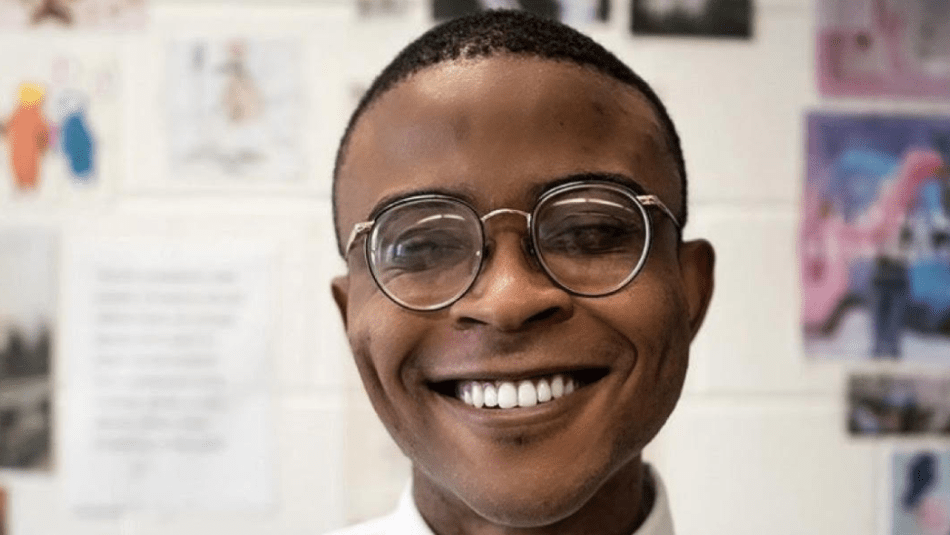 Man wearing glasses and a white dress shirt smiling at the camera