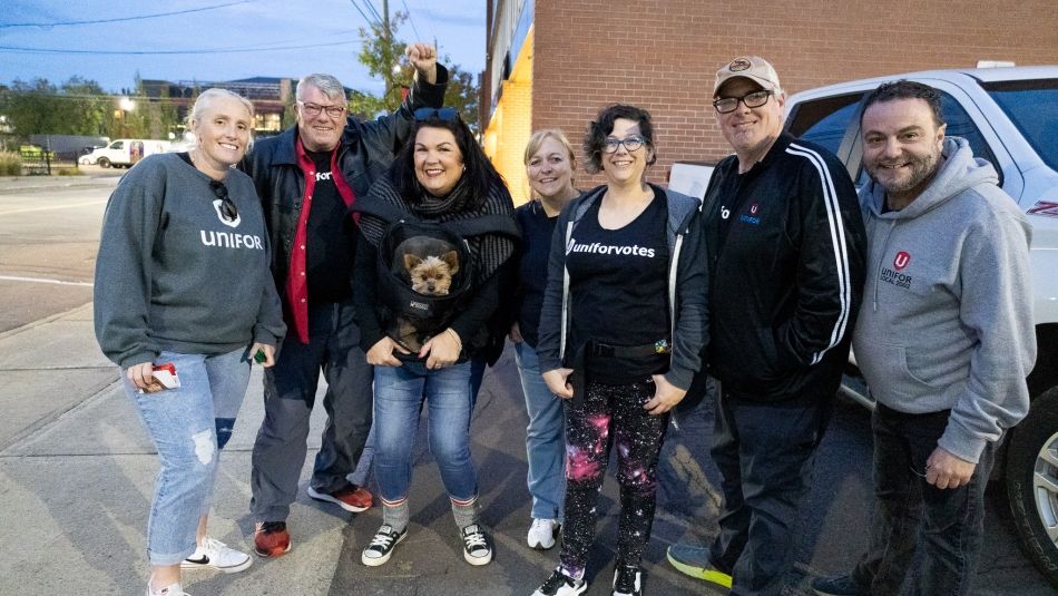 A group of Unifor members stand shoulder to shoulder after an evening of canvassing