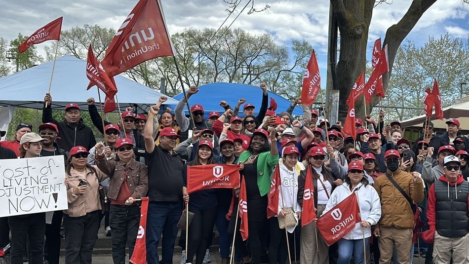 A large group of people outside holding flags and place cards