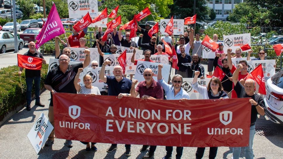 a large crowd standing behind a banner that reads; Unifor a union for everyone.