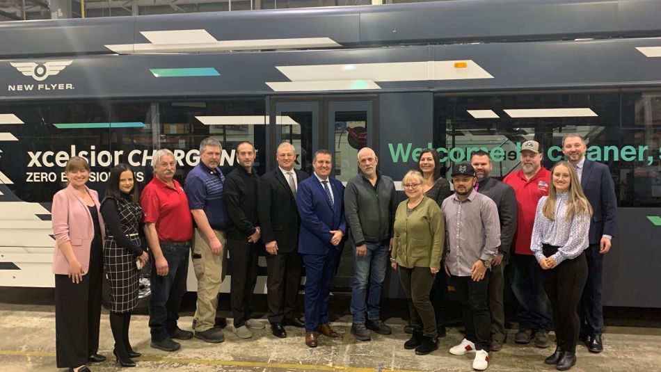 People standing in front of New Flyer bus at funding announcement 