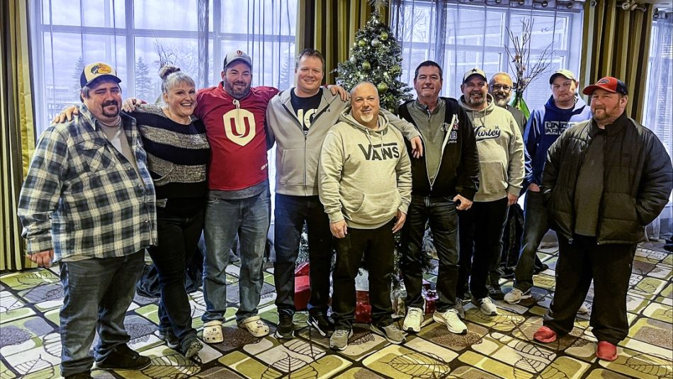 Ten people standing to pose for a photo, many with their arms around eachother.