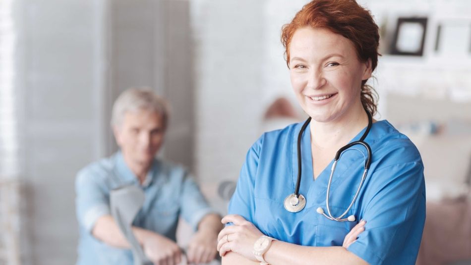 A nurse smiling with a patient in the backround